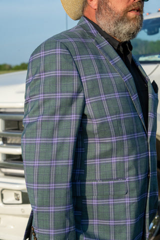 Man wearing a green and purple plaid jacket with a blurred background