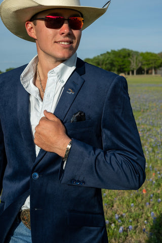 Man in a cowboy hat and suit standing in a field with wildflowers