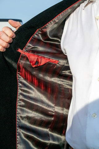 Close-up of a black jacket with red lining and a white shirt underneath.