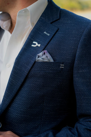 Navy blue suit jacket with a white shirt and pocket square, blurred background