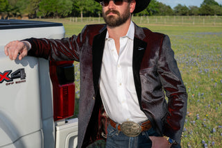 Man in a suit standing next to a truck in a field