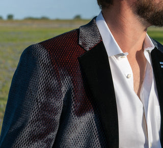 Person wearing a patterned blazer with a white shirt outdoors